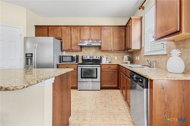 kitchen with light stone countertops, tasteful backsplash, stainless steel appliances, sink, and light tile patterned floors