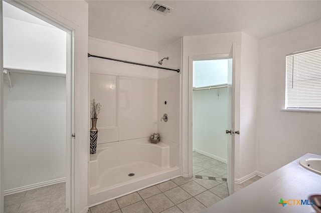 bathroom with walk in shower, a healthy amount of sunlight, and tile patterned floors