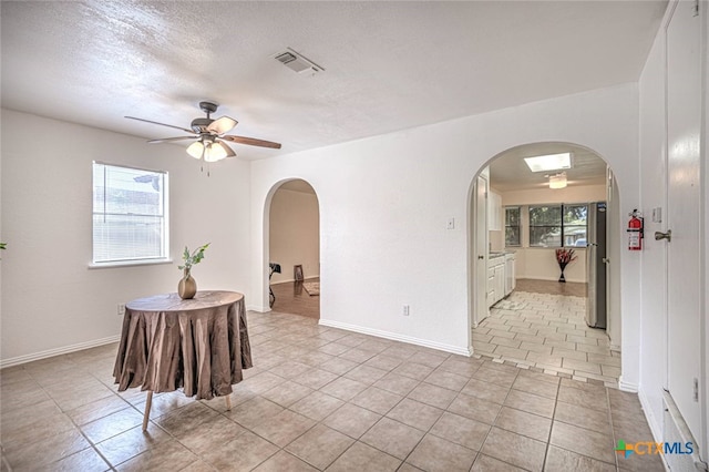 empty room featuring ceiling fan, a textured ceiling, and light tile patterned floors