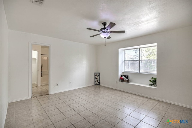 tiled spare room with a textured ceiling and ceiling fan