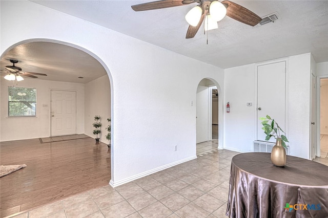 unfurnished dining area with ceiling fan, a textured ceiling, and light hardwood / wood-style flooring