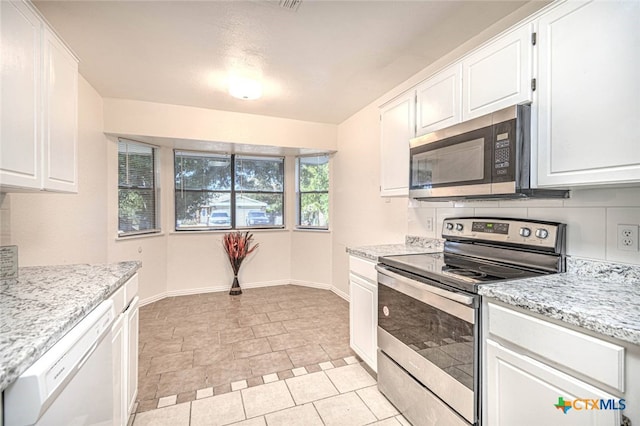 kitchen featuring white cabinets, light stone counters, and appliances with stainless steel finishes