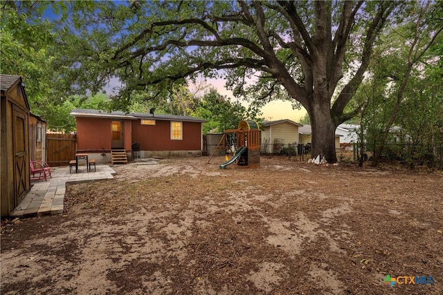 back of house with a fenced backyard, a playground, and a patio area