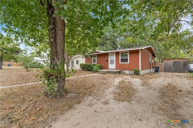ranch-style home featuring fence and dirt driveway