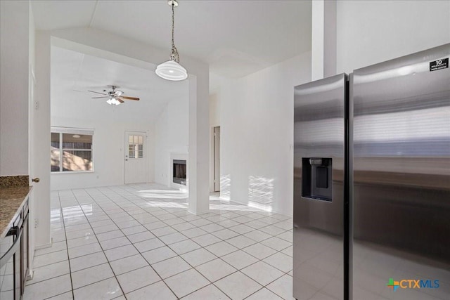 kitchen featuring light tile patterned floors, a ceiling fan, lofted ceiling, a fireplace, and stainless steel refrigerator with ice dispenser