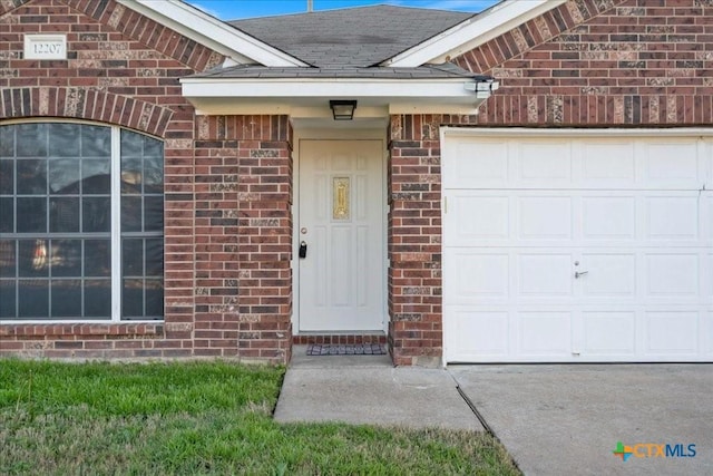 property entrance with a garage, brick siding, and roof with shingles