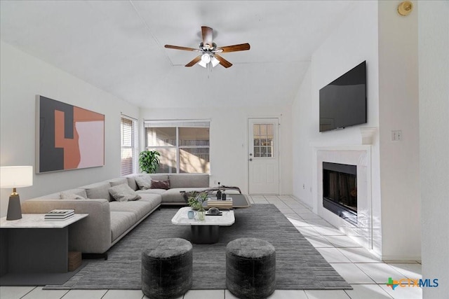 living room featuring light tile patterned floors, a fireplace, a ceiling fan, and lofted ceiling