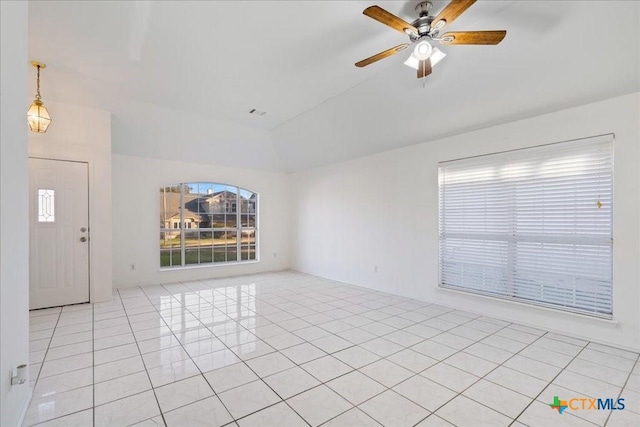 empty room featuring ceiling fan, light tile patterned flooring, and vaulted ceiling