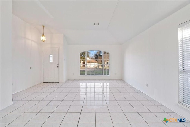 entryway featuring vaulted ceiling, light tile patterned flooring, and visible vents