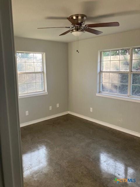 empty room featuring a ceiling fan, baseboards, and finished concrete floors