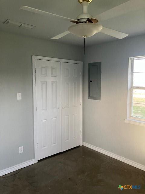 unfurnished bedroom featuring baseboards, electric panel, ceiling fan, a closet, and concrete flooring