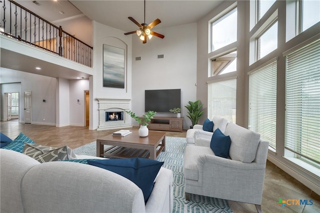 934 Wilderness Trl, New Braunfels, TX 78132 - living room featuring a high ceiling, plenty of natural light, baseboards, ceiling fan, and a lit fireplace