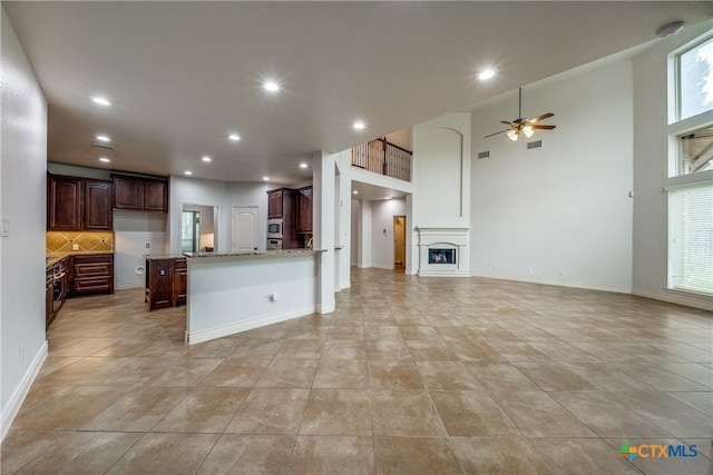 934 Wilderness Trl, New Braunfels, TX 78132 - kitchen with open floor plan, a ceiling fan, decorative backsplash, light stone countertops, and recessed lighting