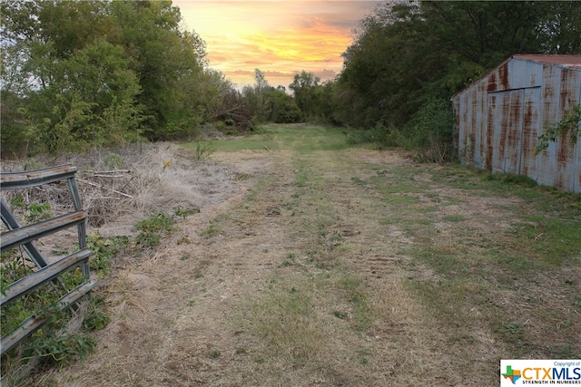 yard at dusk featuring an outdoor structure