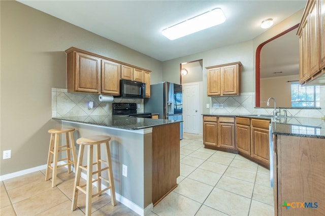 612 Weeping Willow Dr, Temple, TX 76502 - kitchen with black appliances, light tile patterned flooring, a peninsula, and backsplash