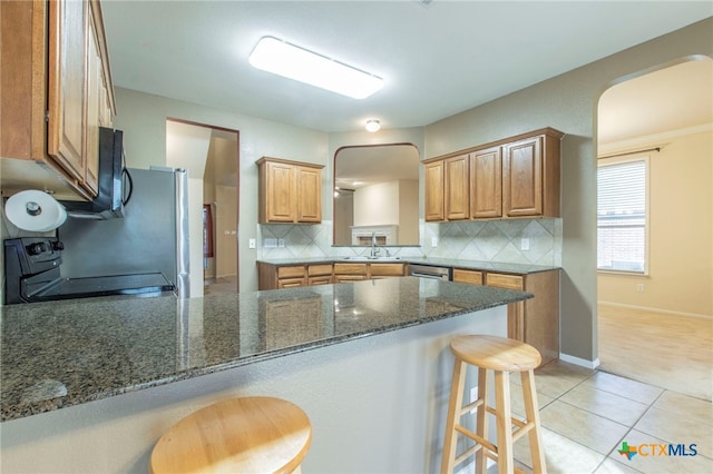 612 Weeping Willow Dr, Temple, TX 76502 - kitchen with range, arched walkways, a peninsula, a breakfast bar area, and black microwave