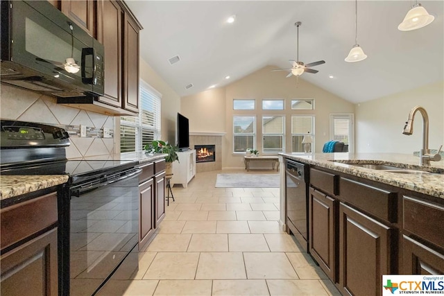 kitchen with black appliances, sink, light stone countertops, a fireplace, and dark brown cabinets