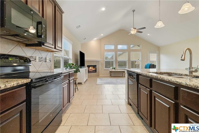 kitchen featuring black appliances, a sink, ceiling fan, a fireplace, and vaulted ceiling