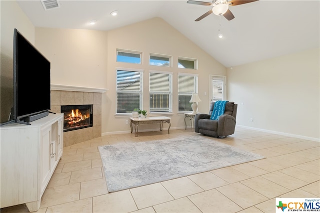 living area featuring high vaulted ceiling, a tiled fireplace, ceiling fan, and light tile patterned flooring