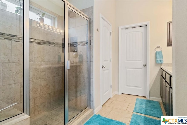 full bath featuring a stall shower, tile patterned floors, baseboards, and vanity