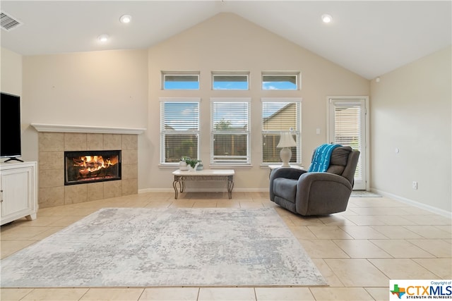 living area featuring light tile patterned floors, high vaulted ceiling, and a tiled fireplace