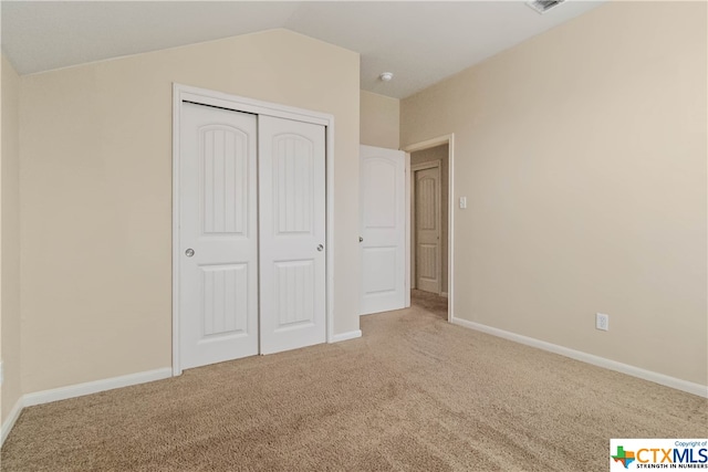 unfurnished bedroom featuring a closet, carpet, and lofted ceiling