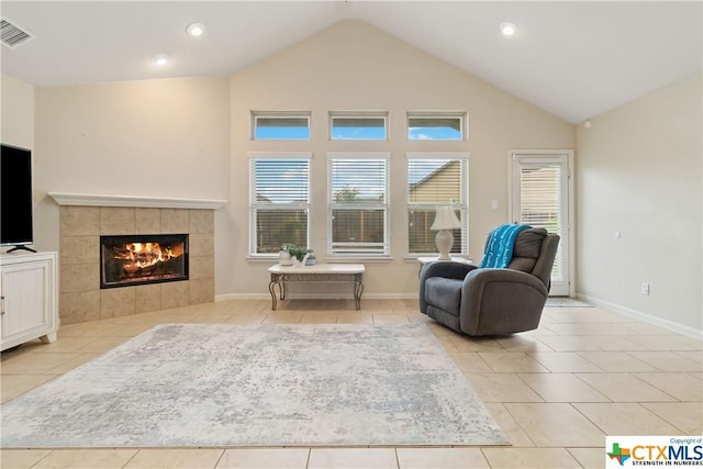 living area with a fireplace, light tile patterned floors, and high vaulted ceiling