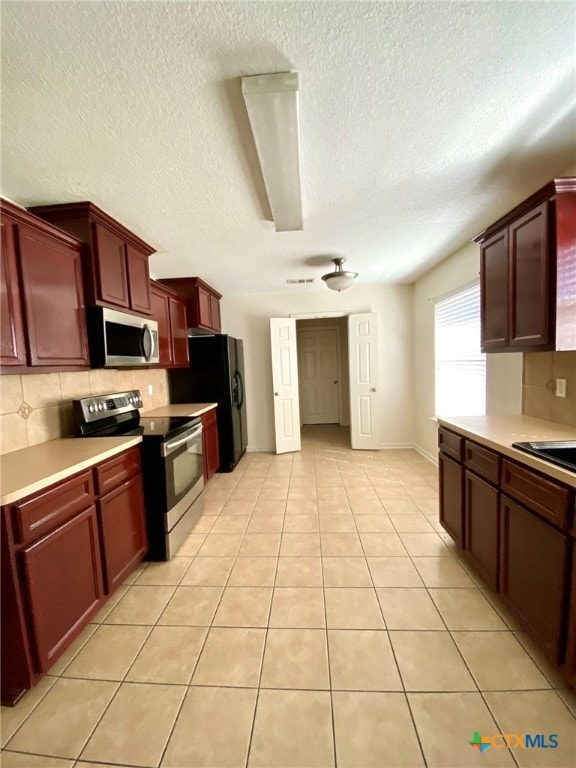 kitchen with decorative backsplash, appliances with stainless steel finishes, a textured ceiling, and light tile patterned floors