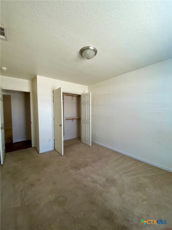 unfurnished bedroom with a closet, carpet, and a textured ceiling