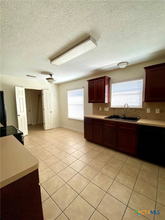 kitchen with black dishwasher, a textured ceiling, sink, and light tile patterned floors