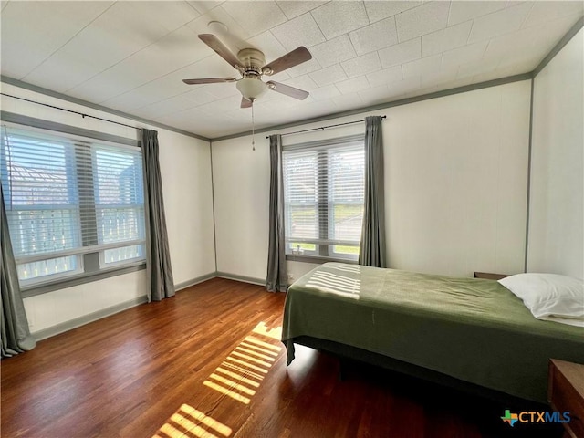 bedroom featuring baseboards, a ceiling fan, wood finished floors, and ornamental molding