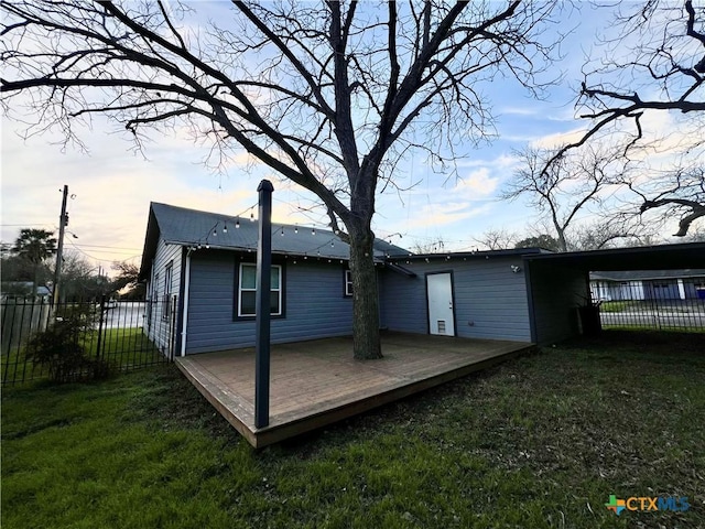 rear view of property with a chimney, fence, a deck, and a lawn