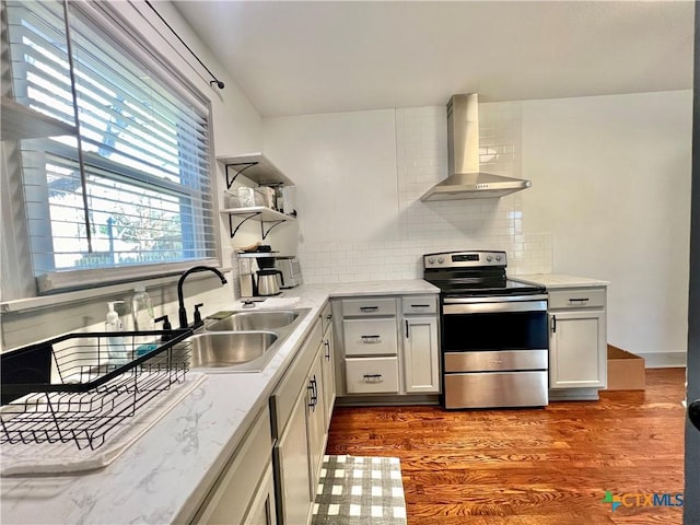 kitchen with wall chimney exhaust hood, wood finished floors, stainless steel range with electric stovetop, open shelves, and backsplash