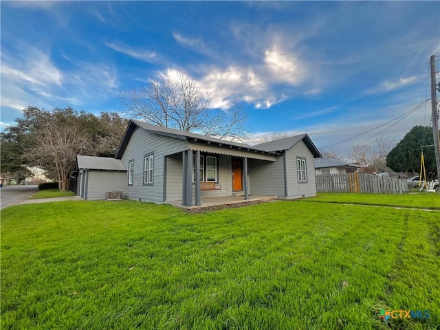 view of front of home with central air condition unit, fence, and a front lawn