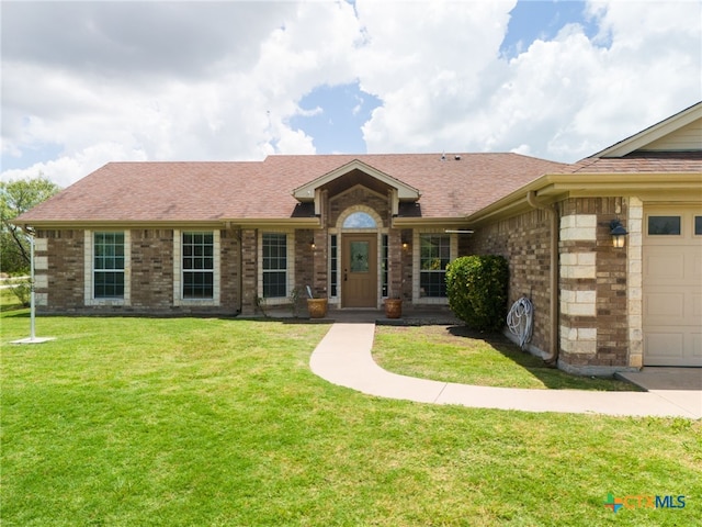 ranch-style house featuring an attached garage, brick siding, roof with shingles, and a front yard