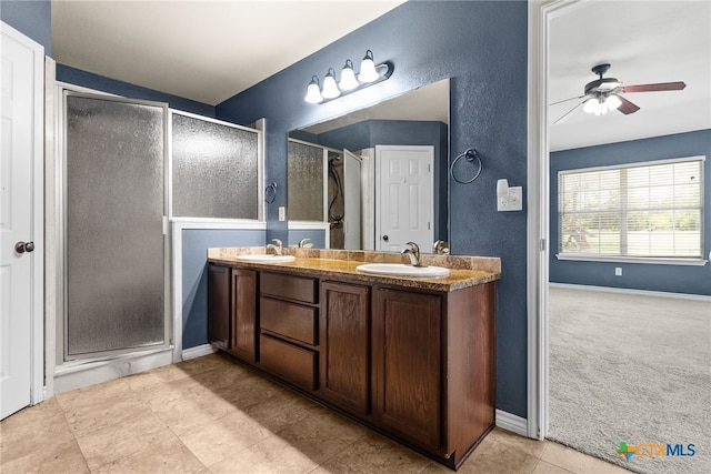 bathroom featuring double vanity, a stall shower, ceiling fan, and a sink