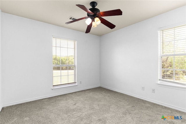 carpeted empty room featuring visible vents, a ceiling fan, and a wealth of natural light