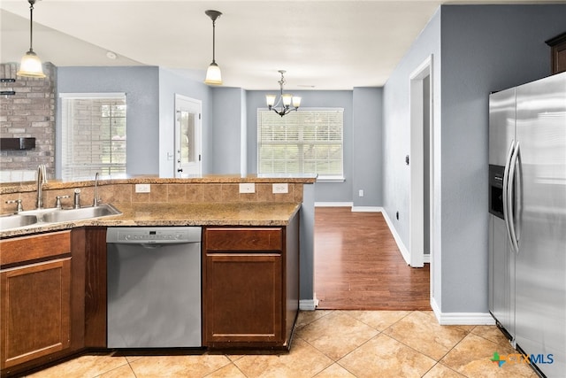 kitchen featuring stainless steel appliances, a sink, an inviting chandelier, decorative light fixtures, and light tile patterned floors