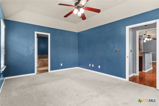 unfurnished bedroom featuring vaulted ceiling, a ceiling fan, connected bathroom, carpet floors, and baseboards
