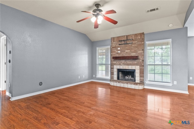 unfurnished living room with wood finished floors, visible vents, a ceiling fan, arched walkways, and baseboards