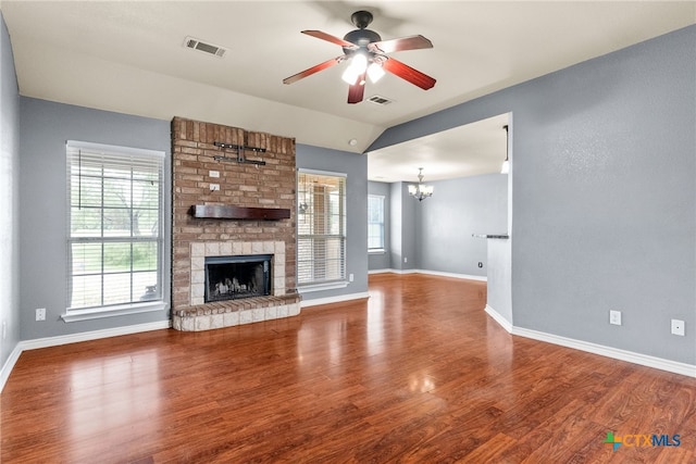 unfurnished living room with a fireplace, wood finished floors, visible vents, and ceiling fan with notable chandelier