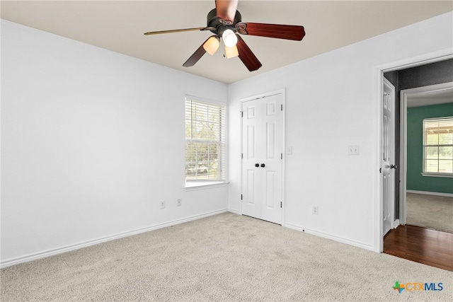 unfurnished bedroom featuring a closet, carpet flooring, baseboards, and a ceiling fan