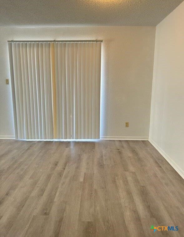 unfurnished room with a textured ceiling and hardwood / wood-style flooring