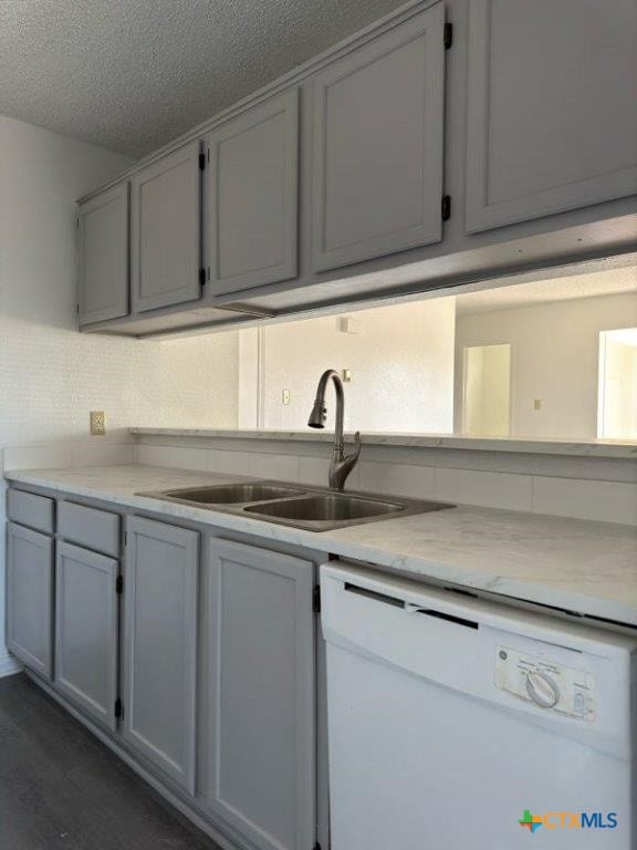 kitchen with white dishwasher, a textured ceiling, and sink