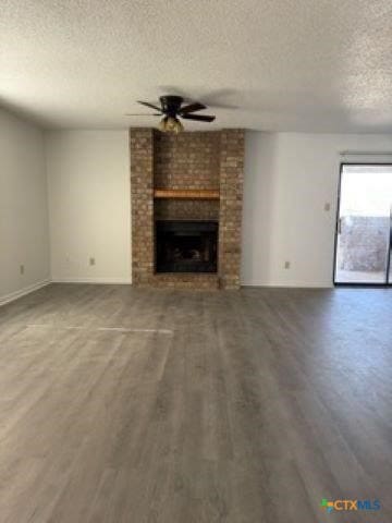 unfurnished living room with a brick fireplace, wood-type flooring, a textured ceiling, and ceiling fan