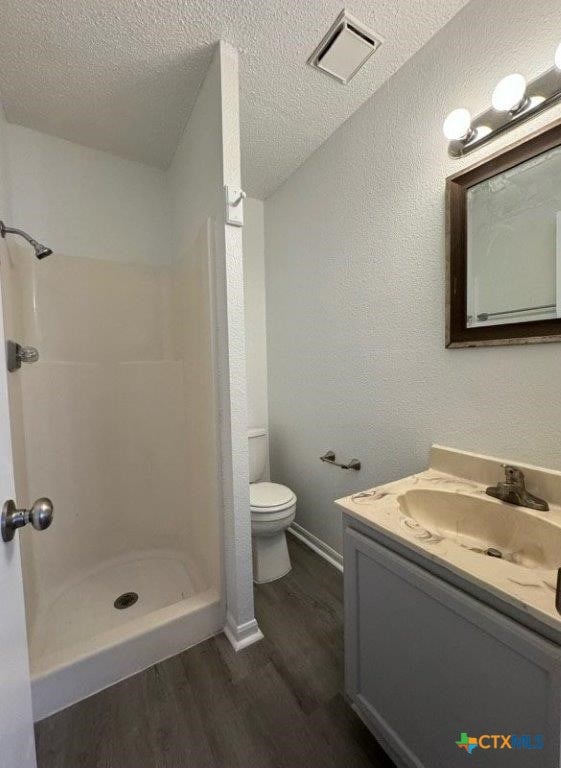 bathroom featuring a shower, vanity, a textured ceiling, and hardwood / wood-style flooring