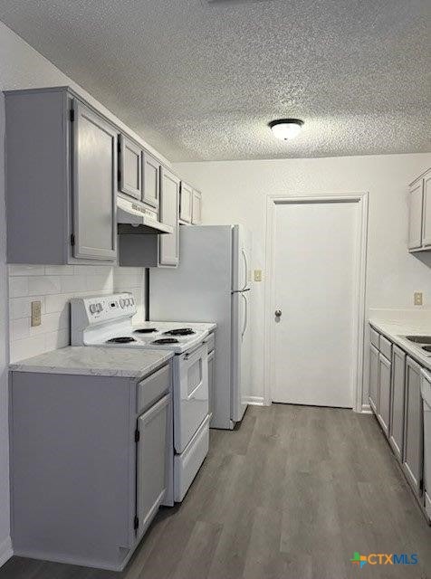 kitchen with dark wood-type flooring, white electric range, gray cabinetry, and decorative backsplash