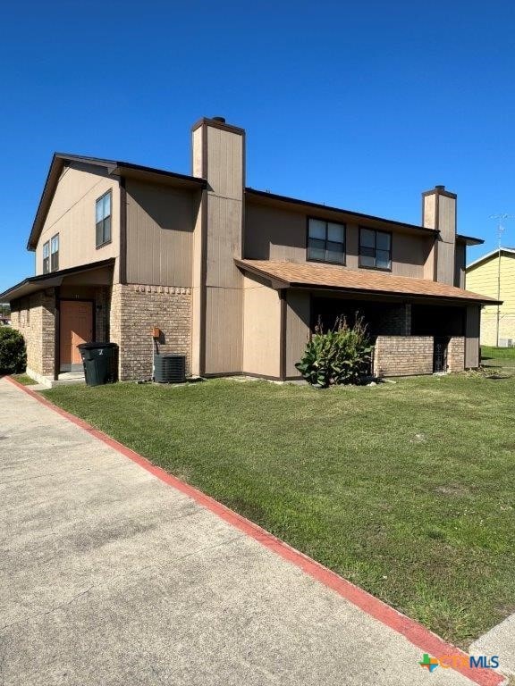 exterior space featuring central AC unit, a garage, and a yard