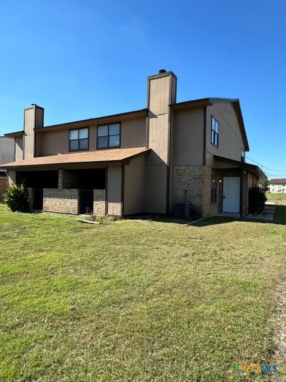 rear view of house featuring central air condition unit and a lawn