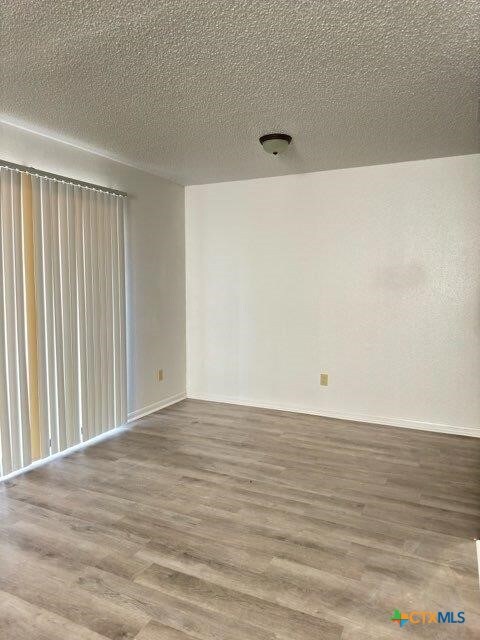 empty room with a textured ceiling and hardwood / wood-style flooring